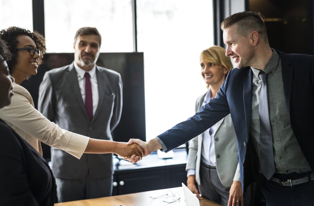 Image showing two clients shaking hands with a Lawgical Group lawyer, symbolizing successful legal partnerships.